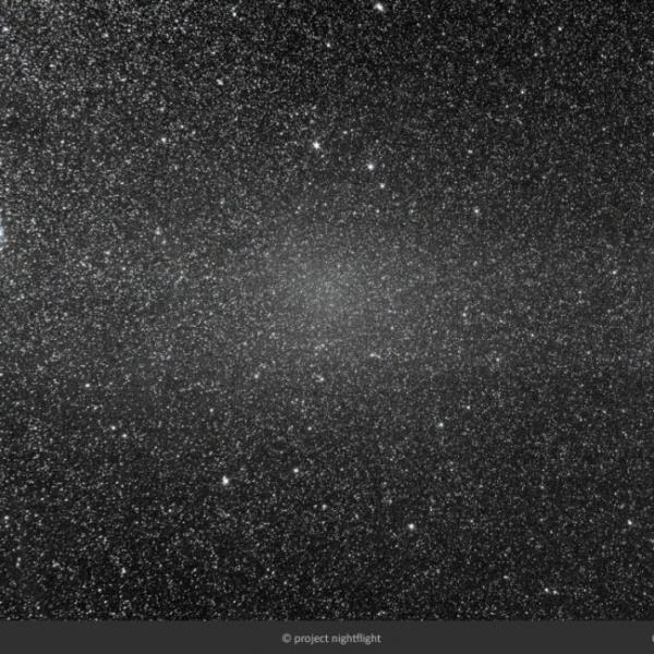 A faint band of light in a very starry sky, with a concentration of light toward the center of the image.